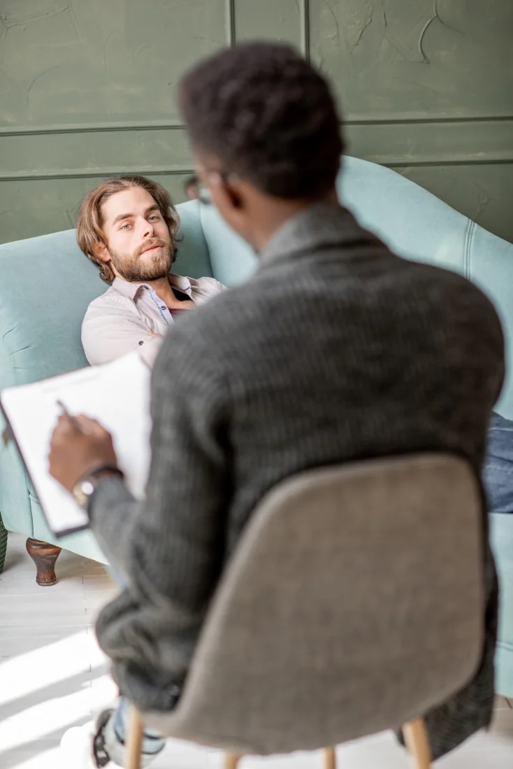 A man lying on a couch talking with his therapist