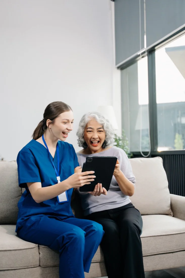 A younger and an older woman smiling together at a tablet