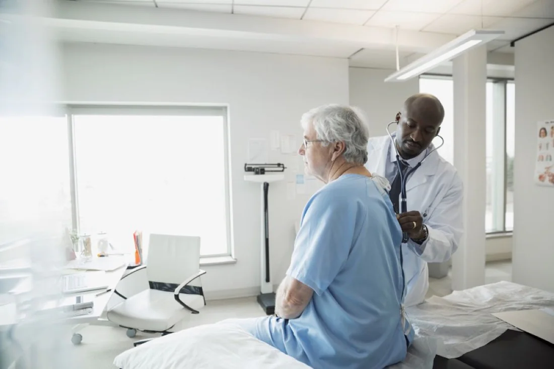 A physician listening to an older patient’s chest during a follow-up