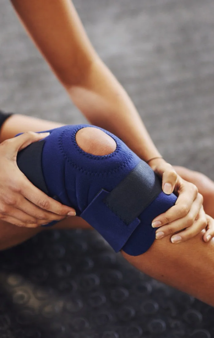 A woman securing a blue knee brace for injury support