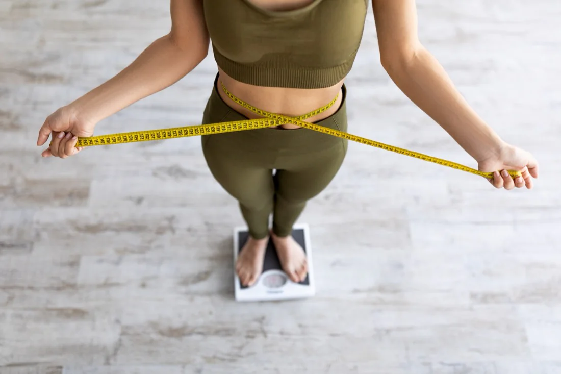 A woman measuring her waist in workout clothes